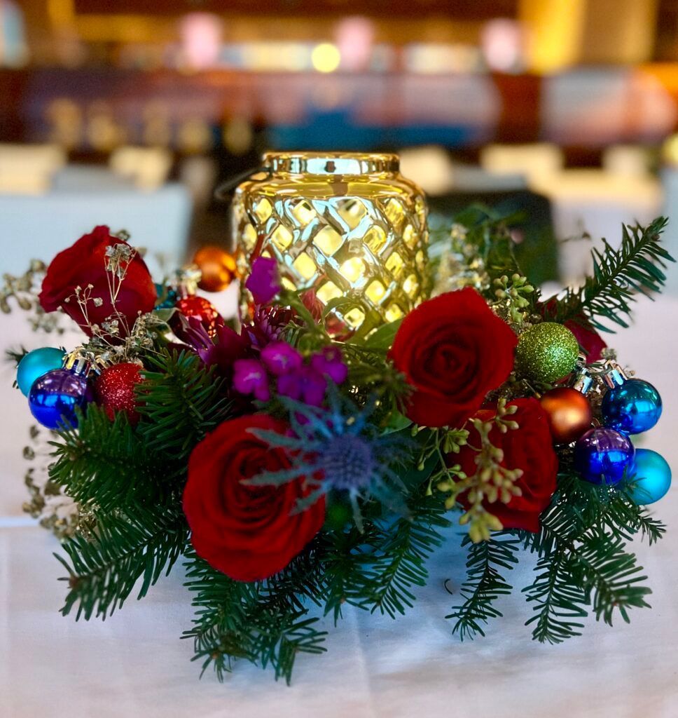 A candle surrounded by flowers and ornaments on a table