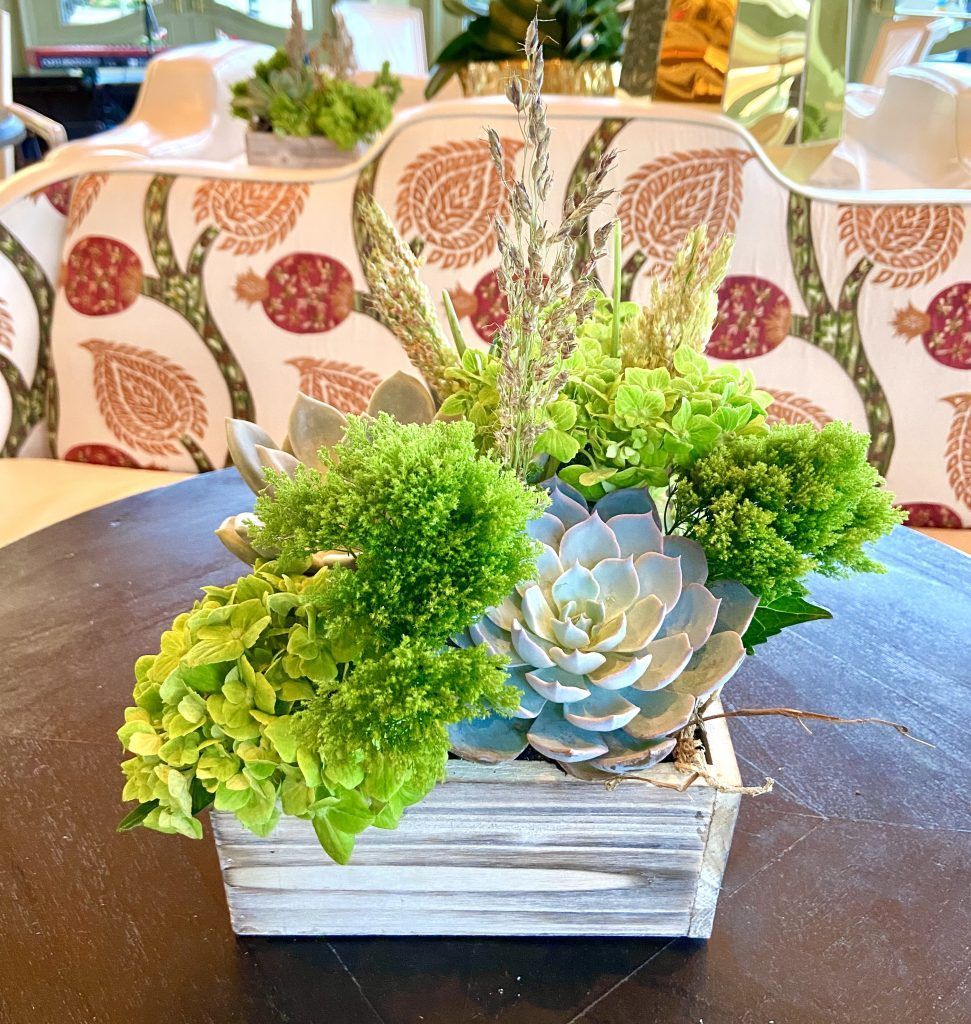 A wooden box filled with green plants sits on a table.