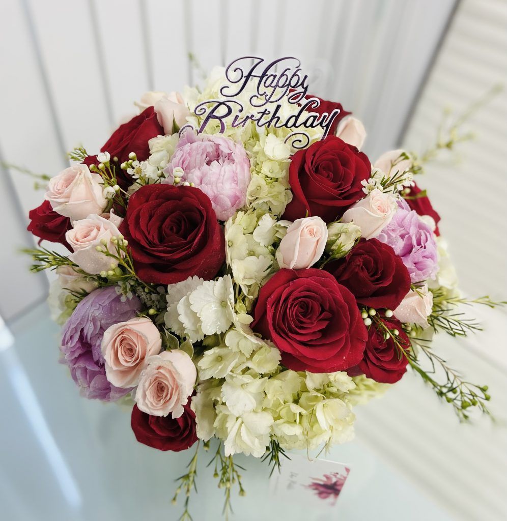 A bouquet of flowers with a happy birthday sign on top