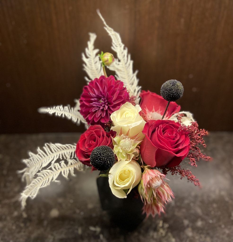 A vase filled with red and white flowers is sitting on a table.