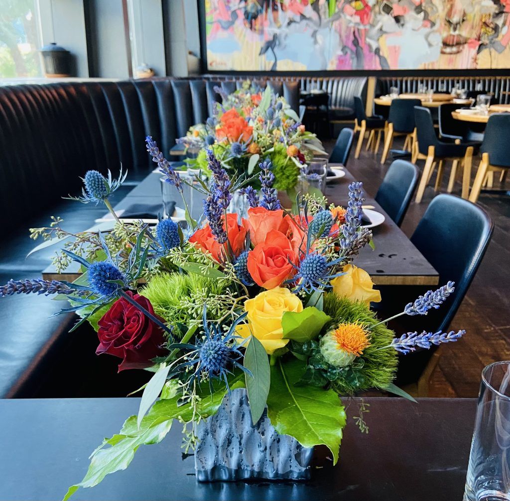 A vase of flowers sits on a table in a restaurant