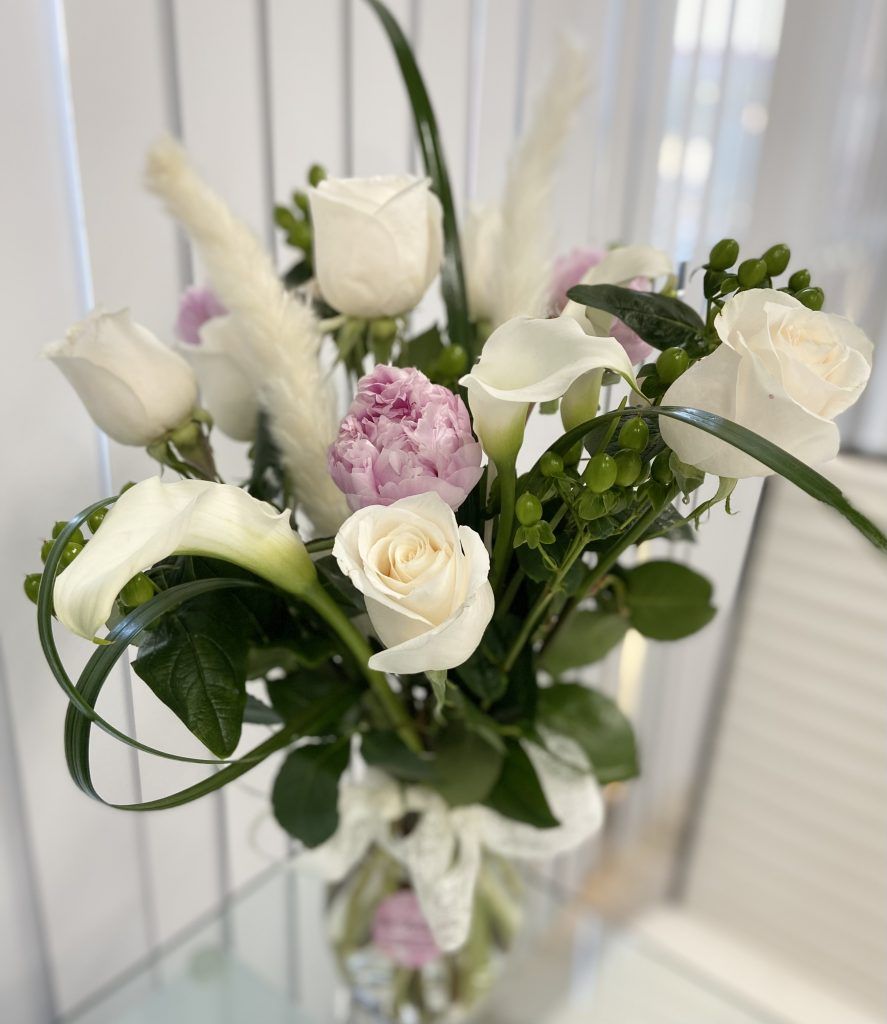A vase filled with white roses and pink peonies is sitting on a table.