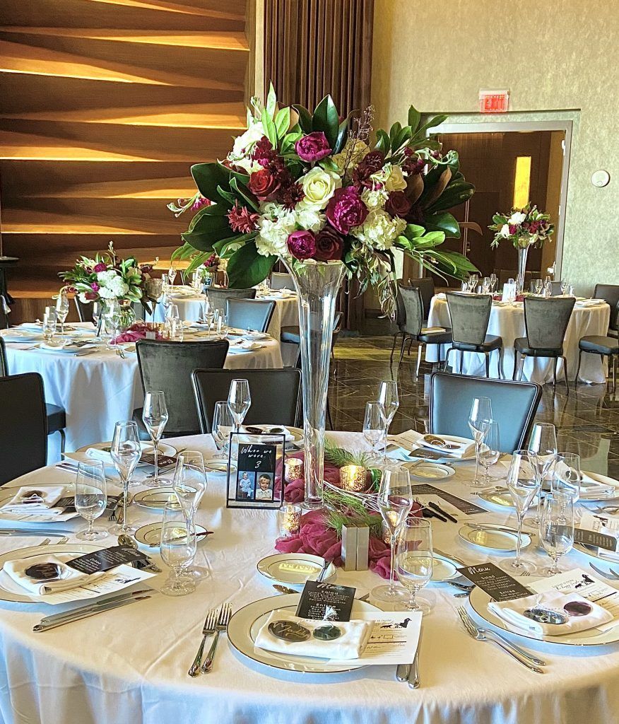 A table set for a wedding reception with a vase of flowers on it.