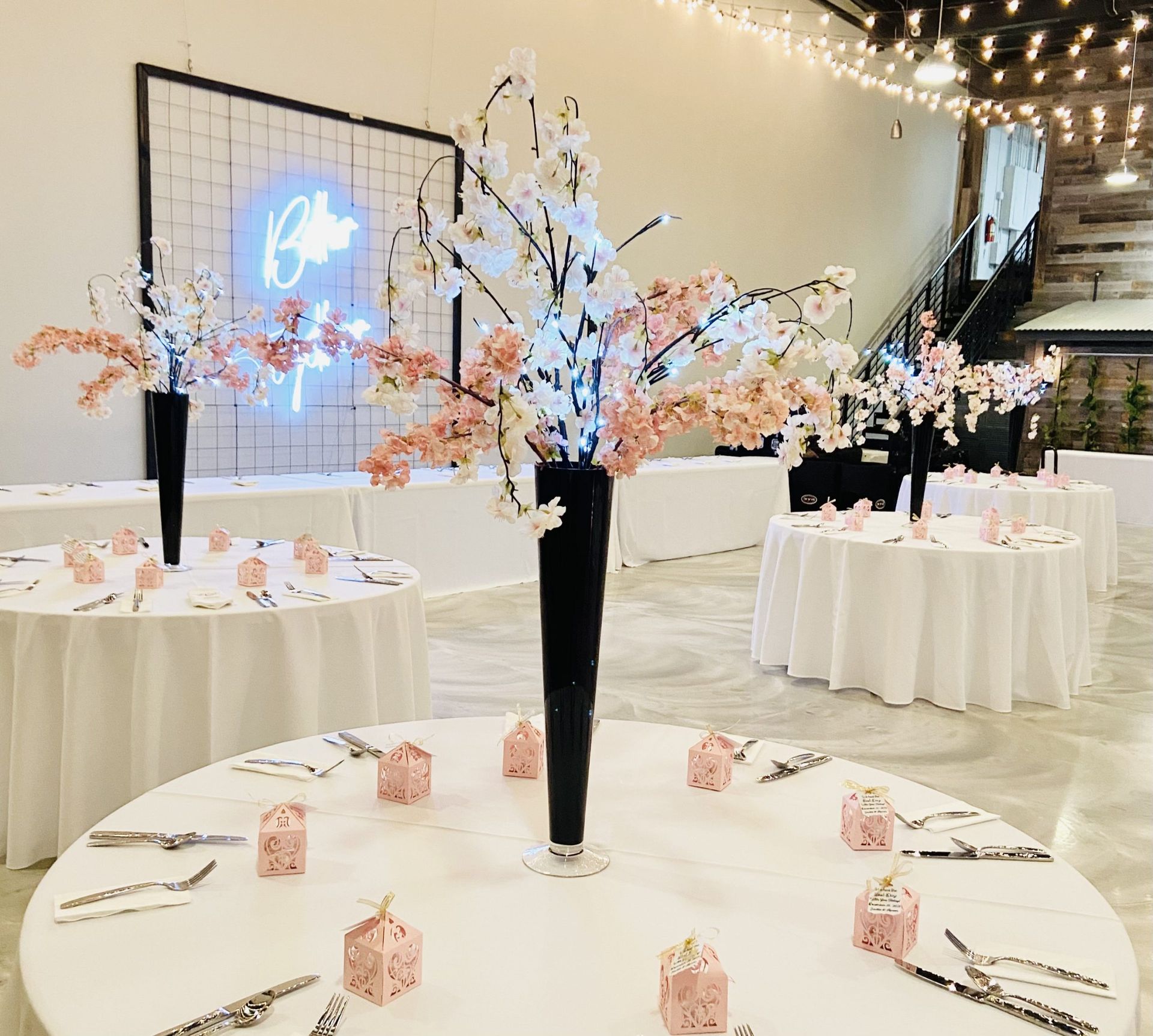 A table set for a wedding reception with a vase of flowers on it.