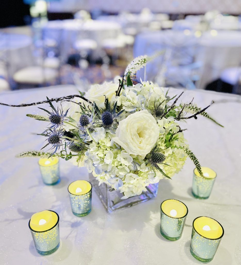 A table with a vase of flowers and candles on it