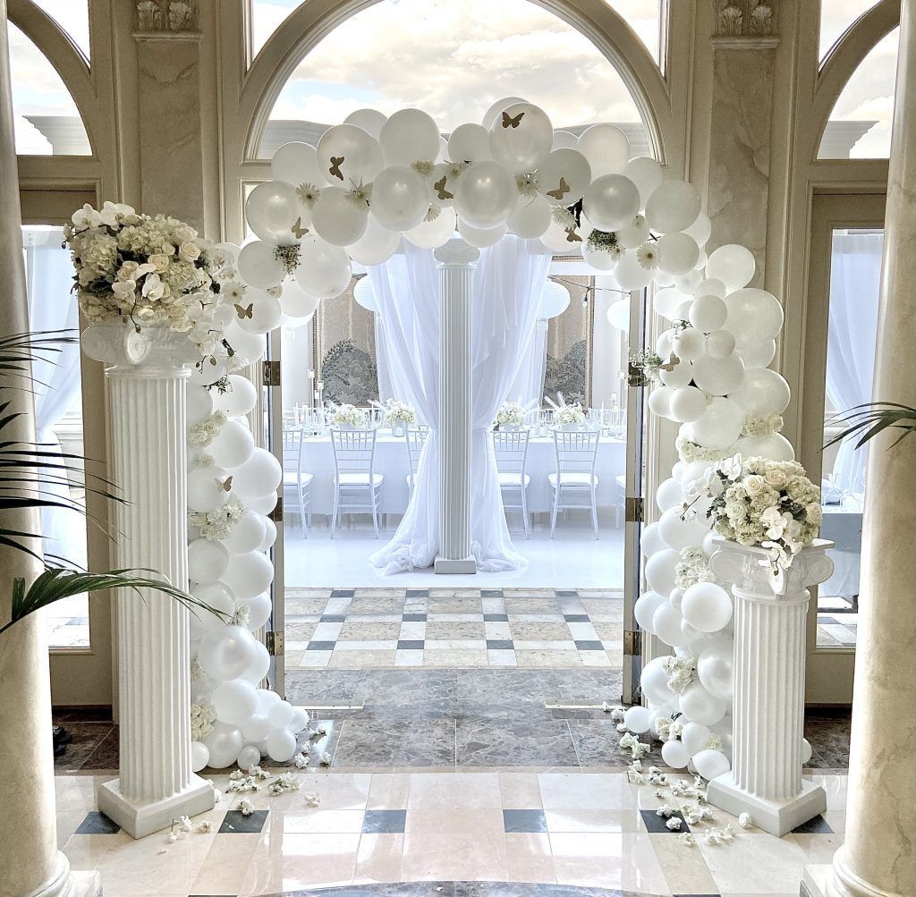 A room decorated with white balloons and flowers.