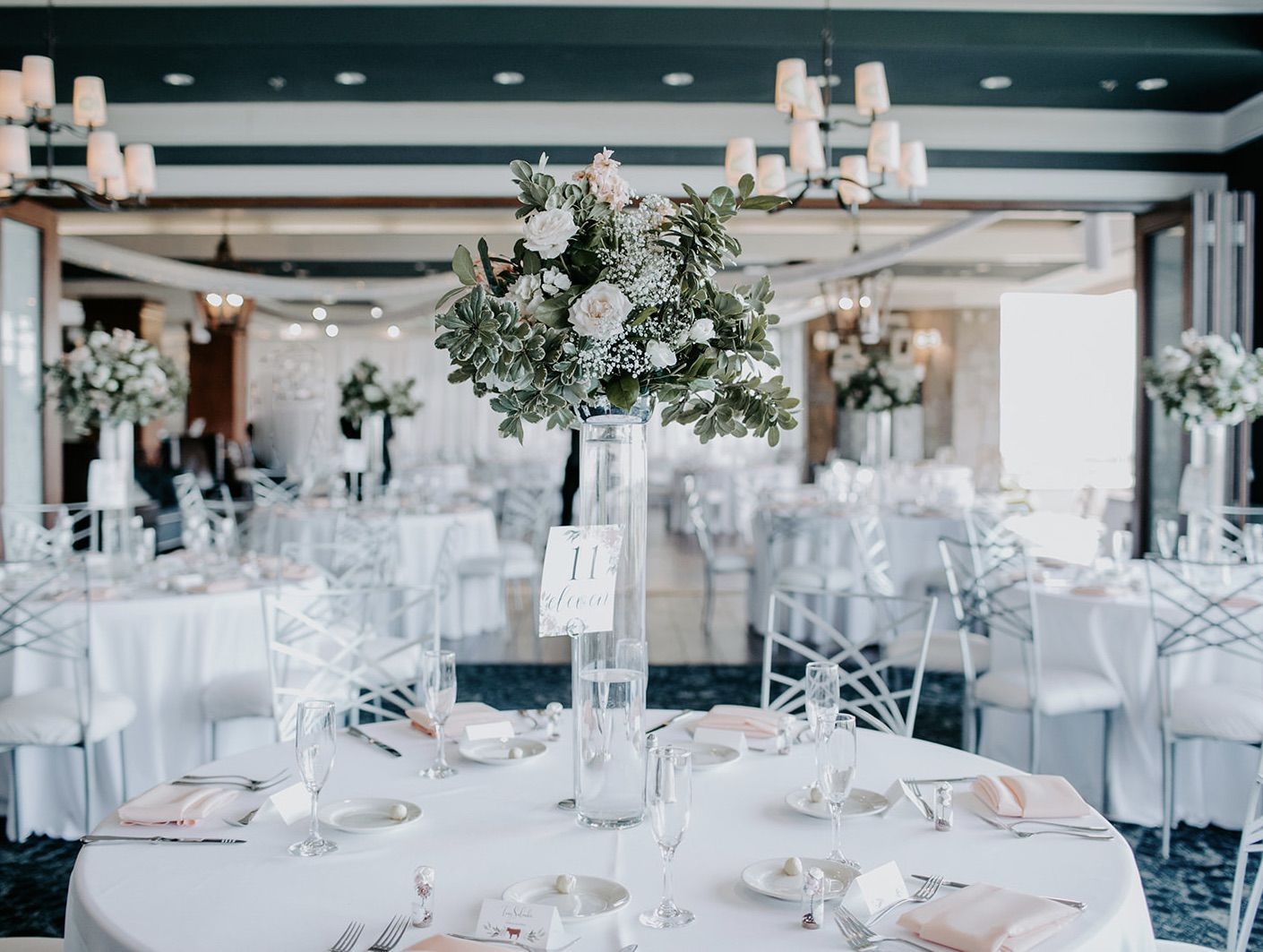 A table set for a wedding reception with a vase of flowers on it.