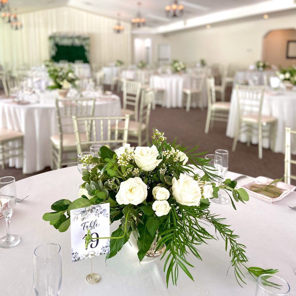 A table with a vase of flowers and a table number on it.