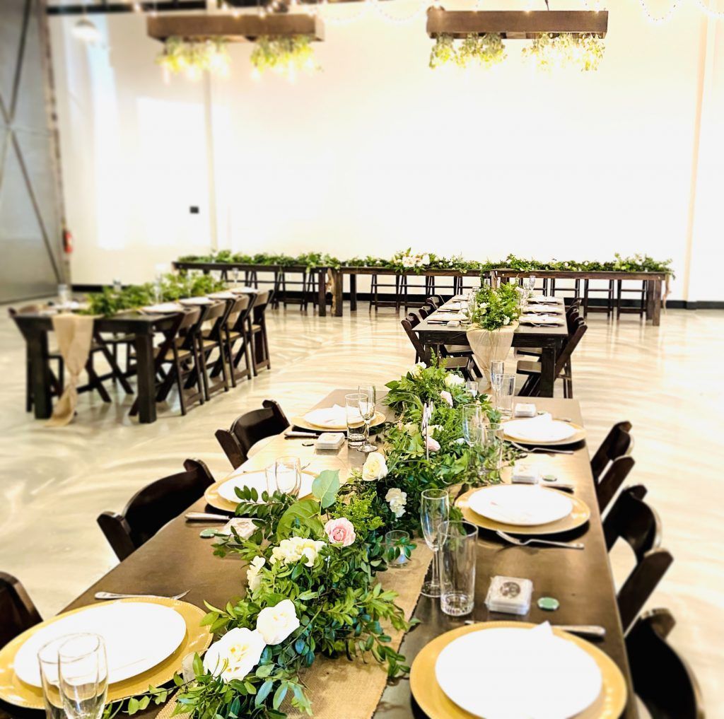 A long table with plates , utensils , and flowers on it in a room.
