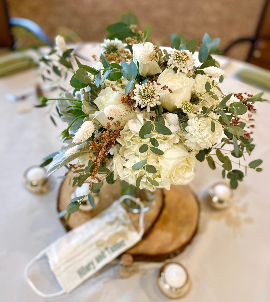 A table with a bouquet of white flowers and a face mask on it.