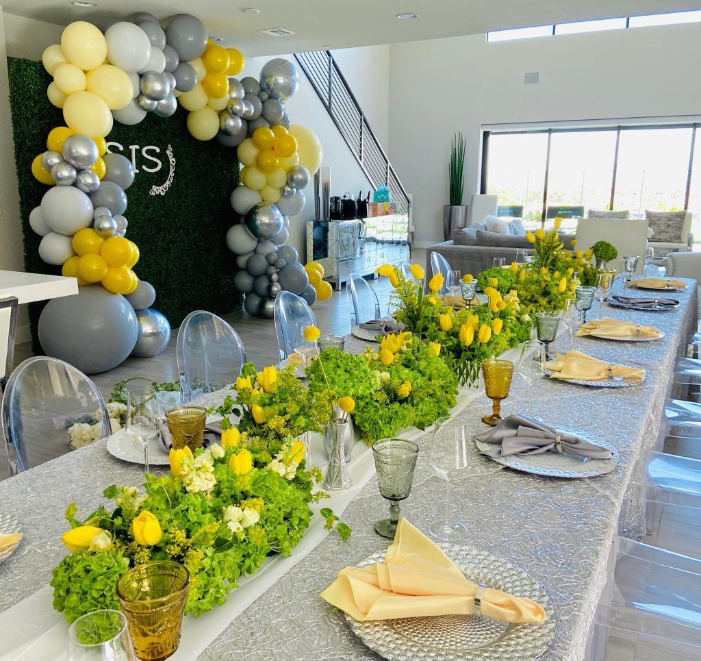 A long table with plates , glasses , and flowers on it.