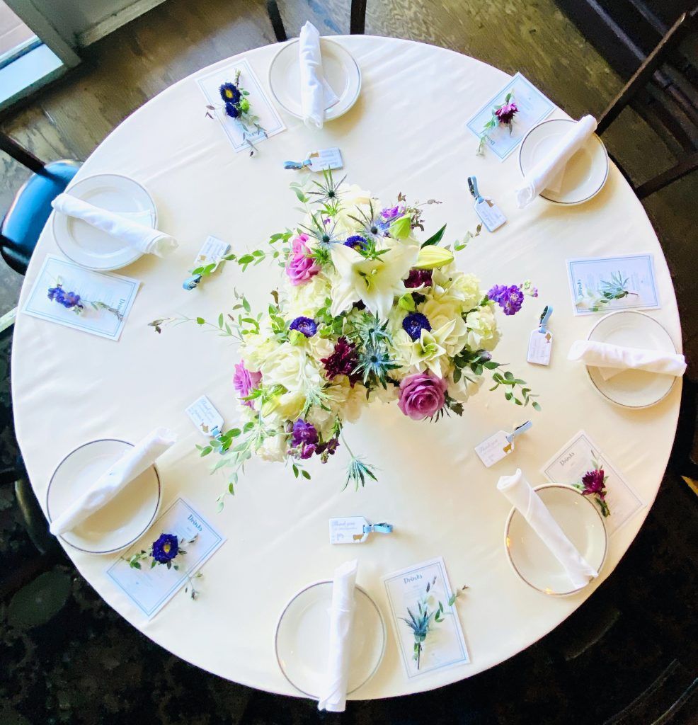 A round table with plates napkins and flowers on it