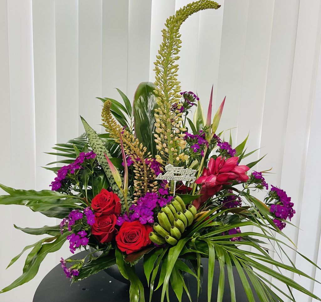 A bouquet of flowers is sitting on a table in front of a window.