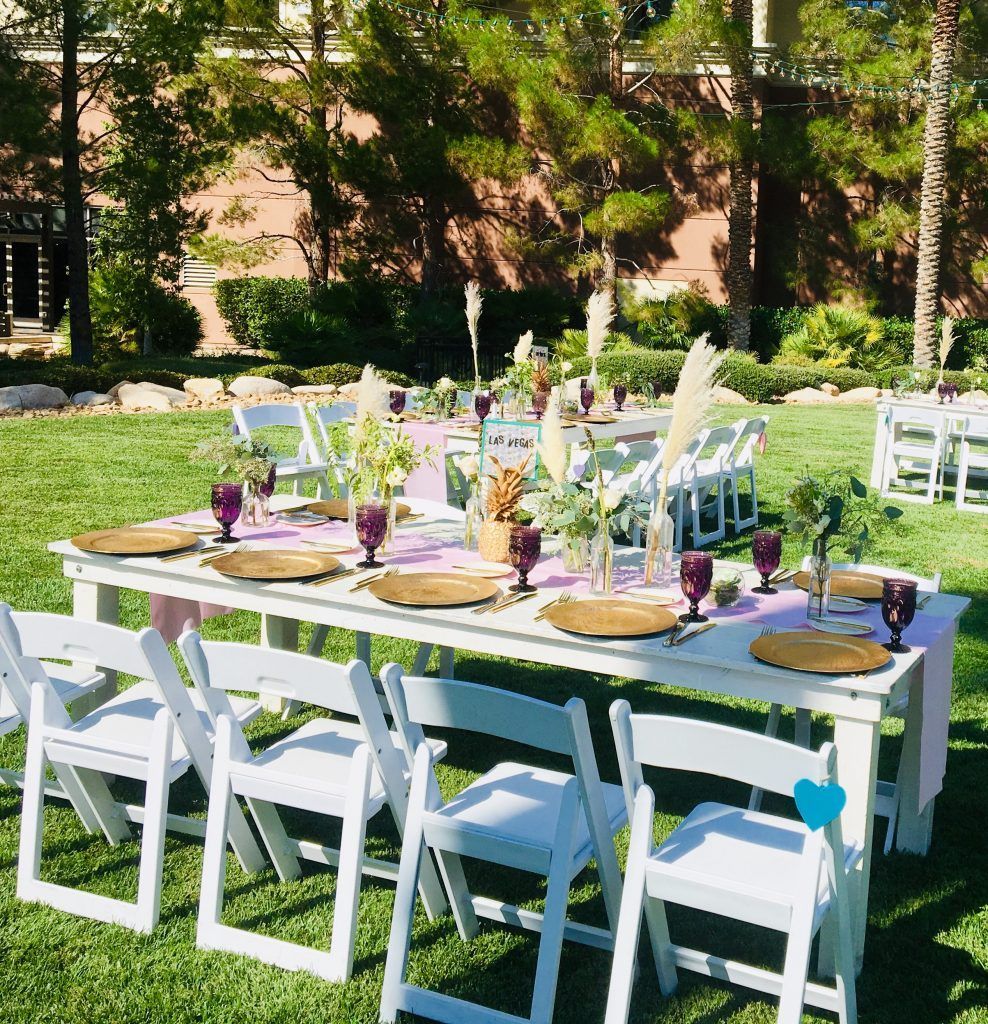 A table and chairs are set up in the grass for a wedding reception.