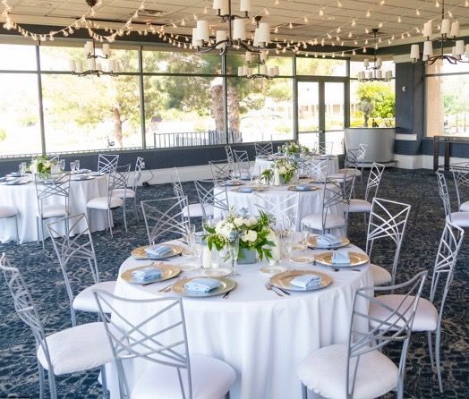 A large room with tables and chairs set up for a wedding reception