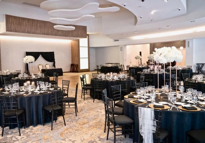 A large room with tables and chairs set up for a wedding reception.