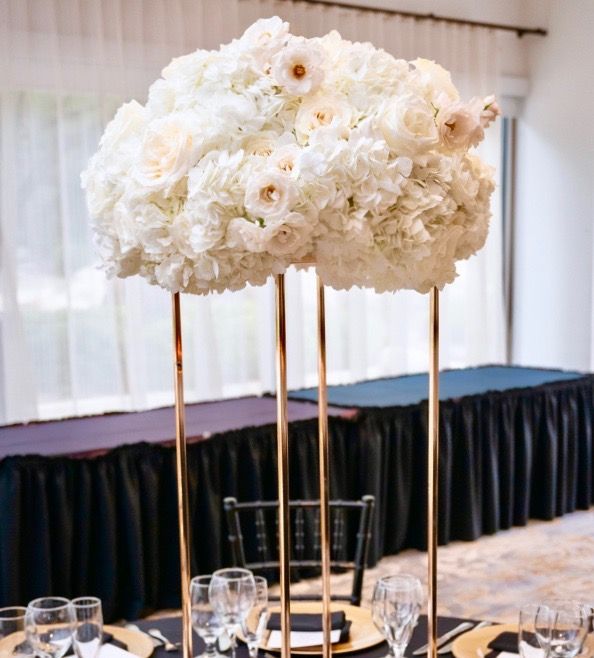 A tall vase filled with white flowers is on a table.