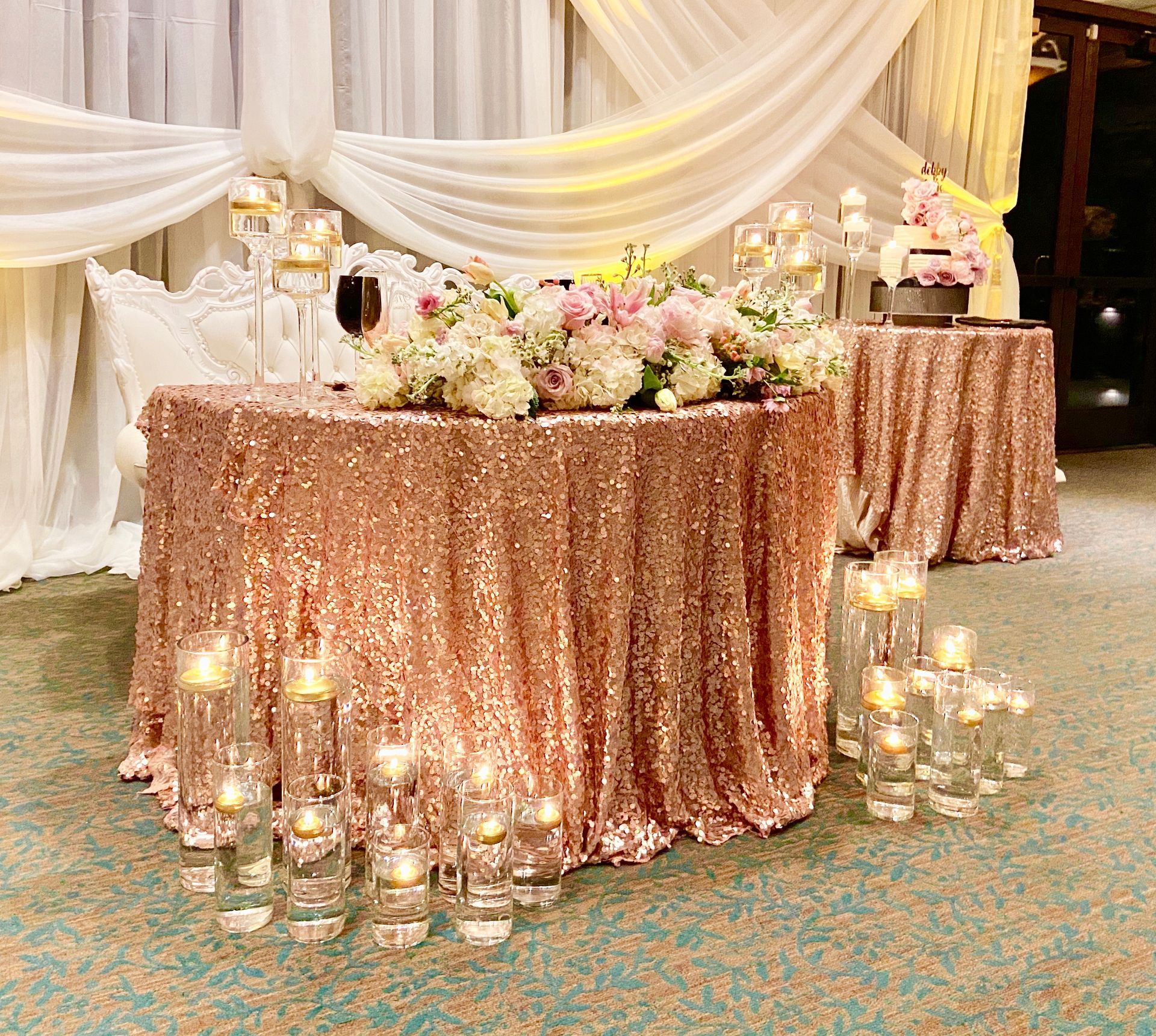 A table with a sequined tablecloth and candles on it.