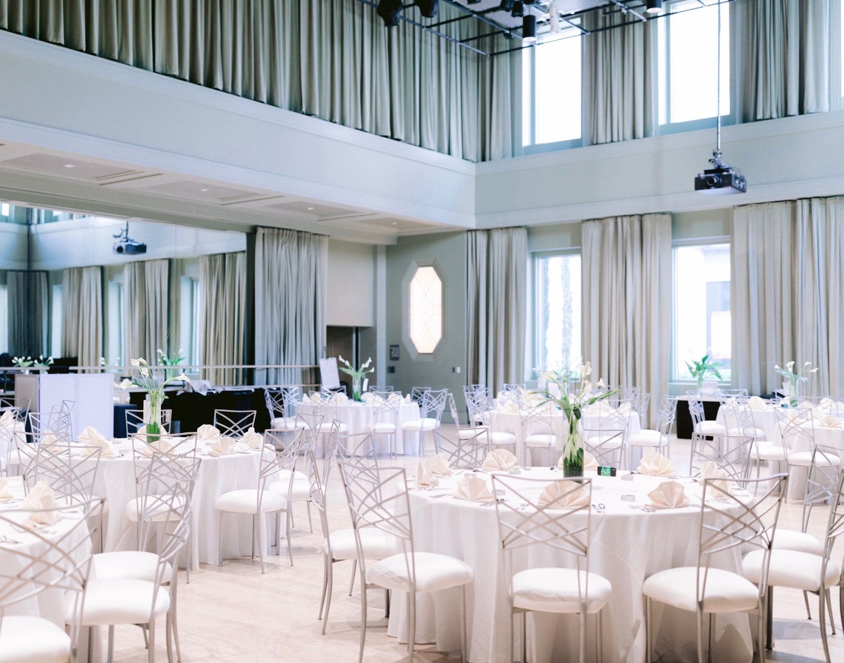 A large room with tables and chairs set up for a wedding reception.
