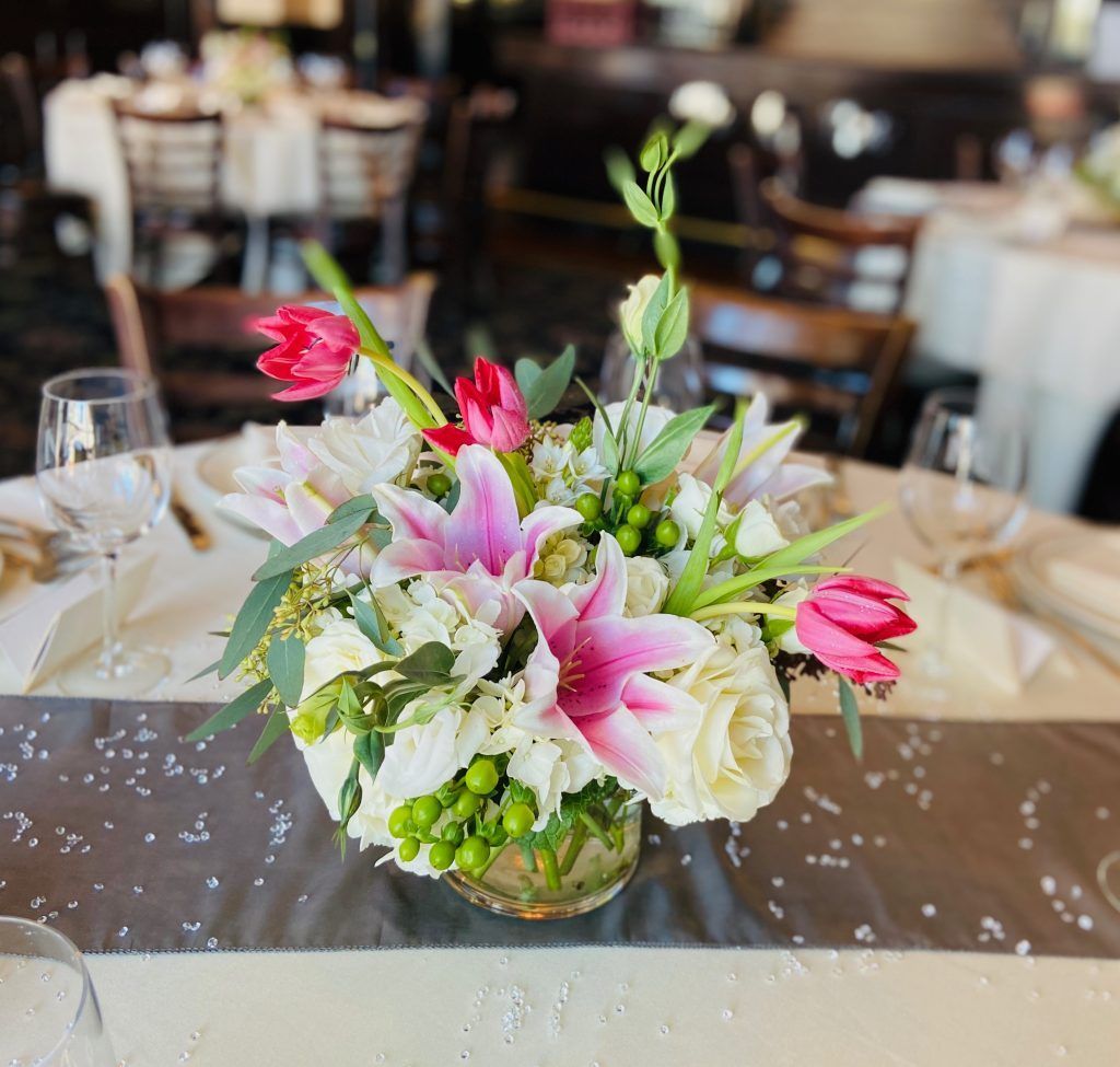 A vase filled with pink and white flowers is on a table.