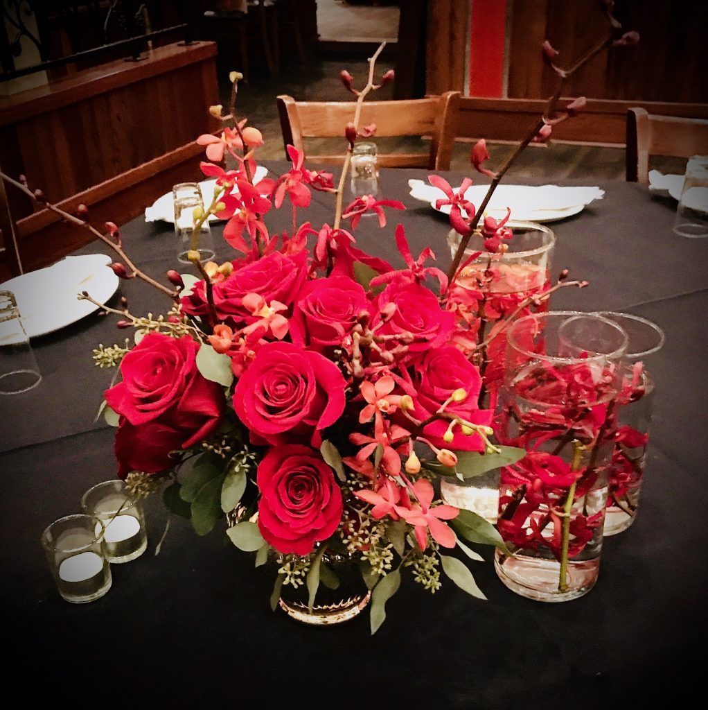 A table with red flowers and candles on it