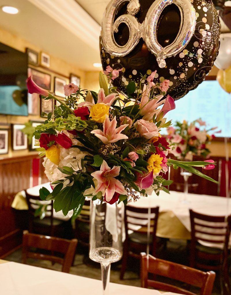 A balloon with the number 60 on it is sitting on top of a vase of flowers.