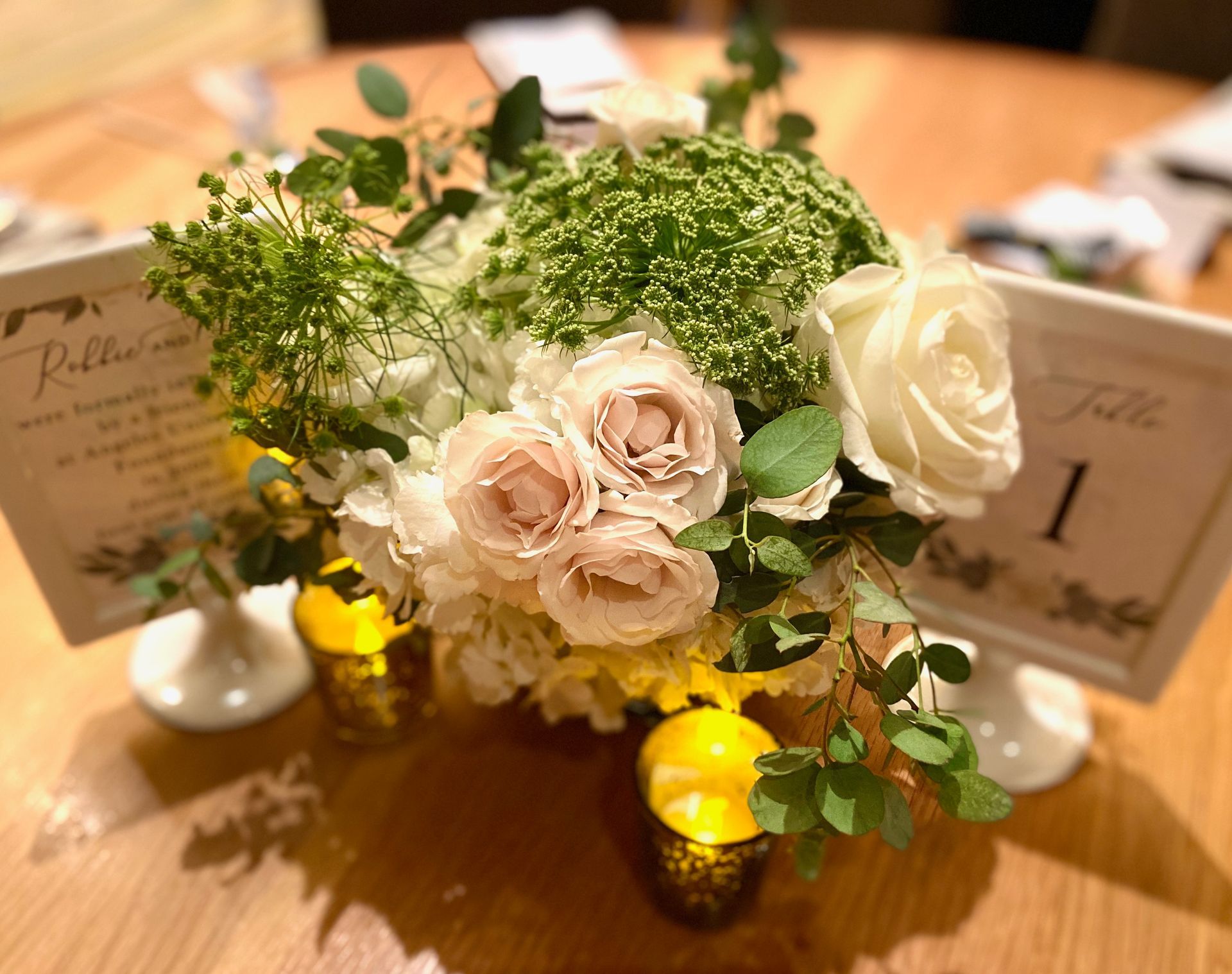A table with a vase of flowers and candles on it.