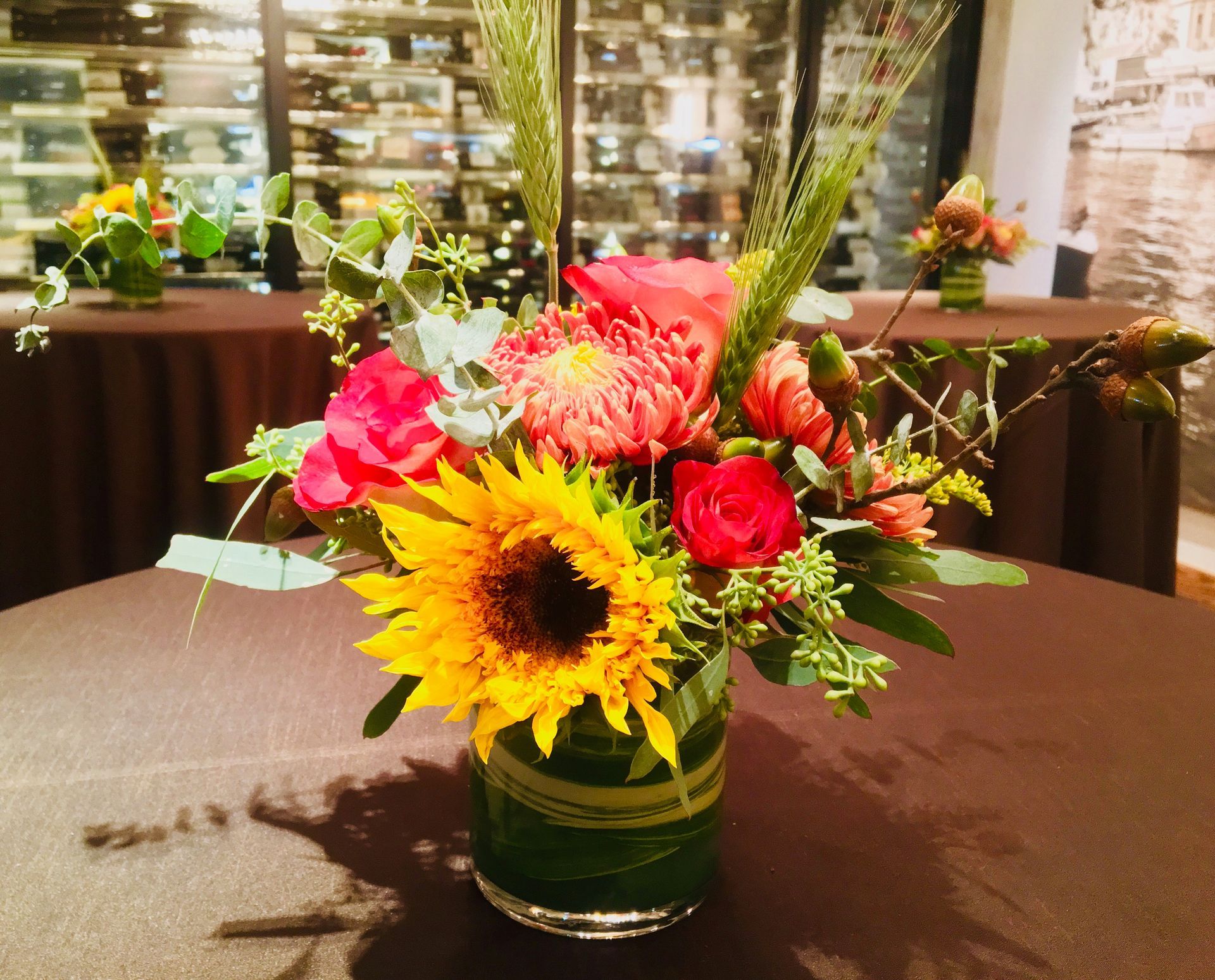 A vase filled with sunflowers and roses sits on a table