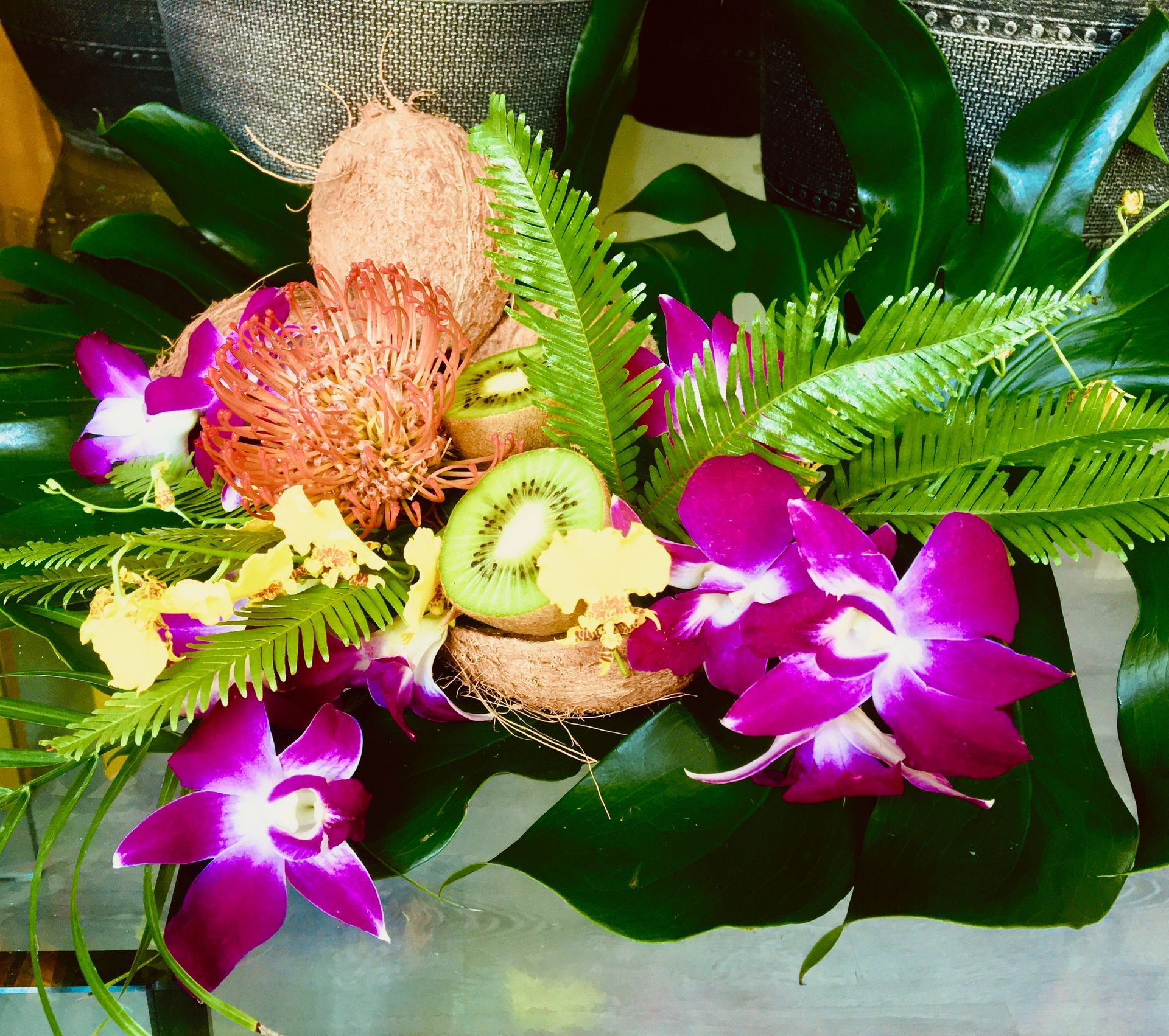 A bouquet of flowers and fruit including kiwi and coconuts