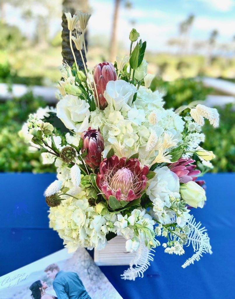 A vase filled with white flowers is sitting on a blue table.