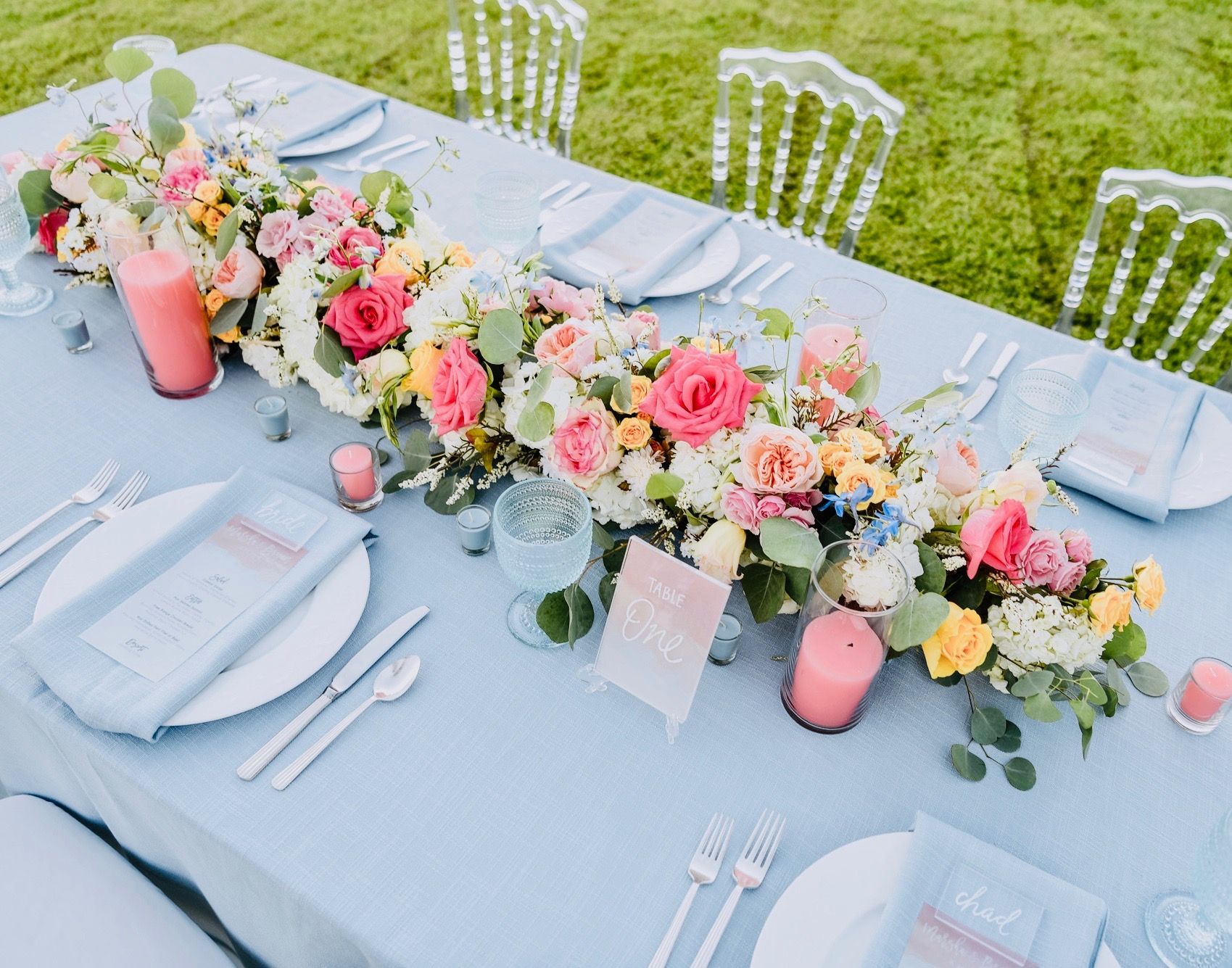 A long table with plates , silverware , candles and flowers on it.