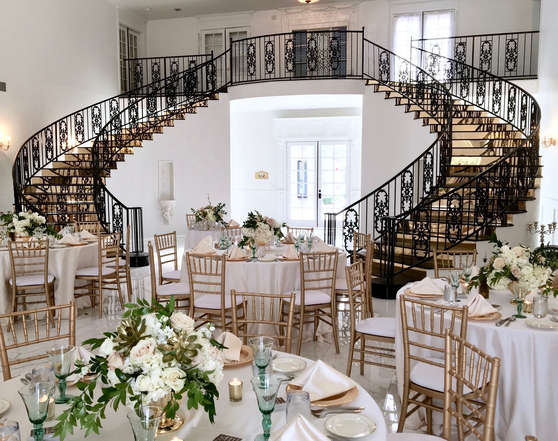 A large room with tables and chairs and a spiral staircase