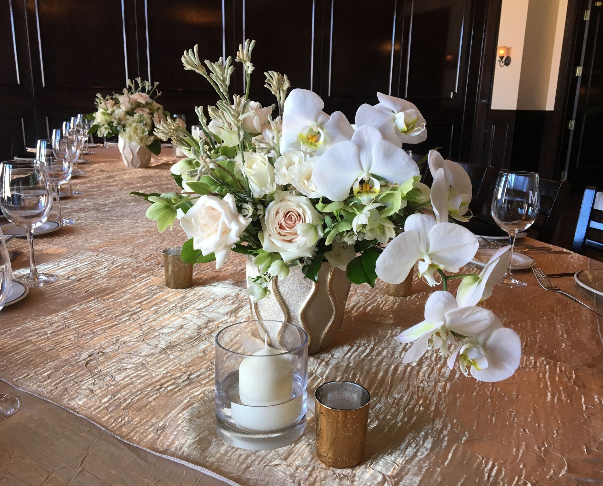 A table with a vase of flowers and a candle on it.