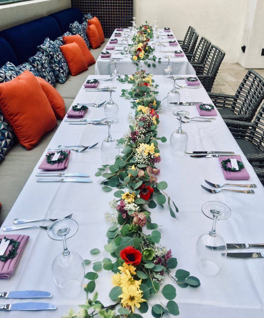 A long table with flowers and utensils on it