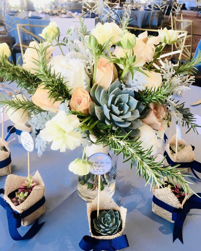 A table with a vase of flowers and succulents on it.