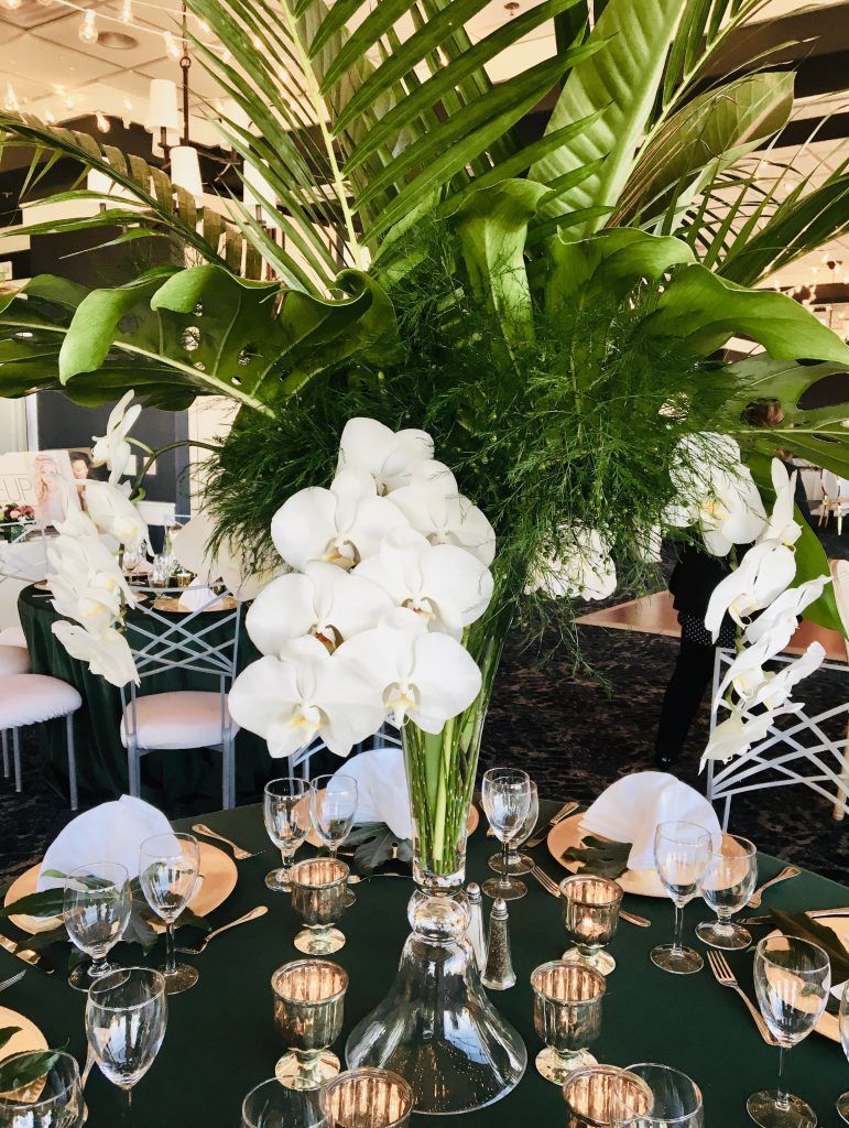 A table set for a wedding reception with a vase of flowers on it.