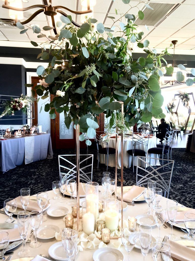 A table set for a wedding reception with a tall vase filled with flowers and candles.