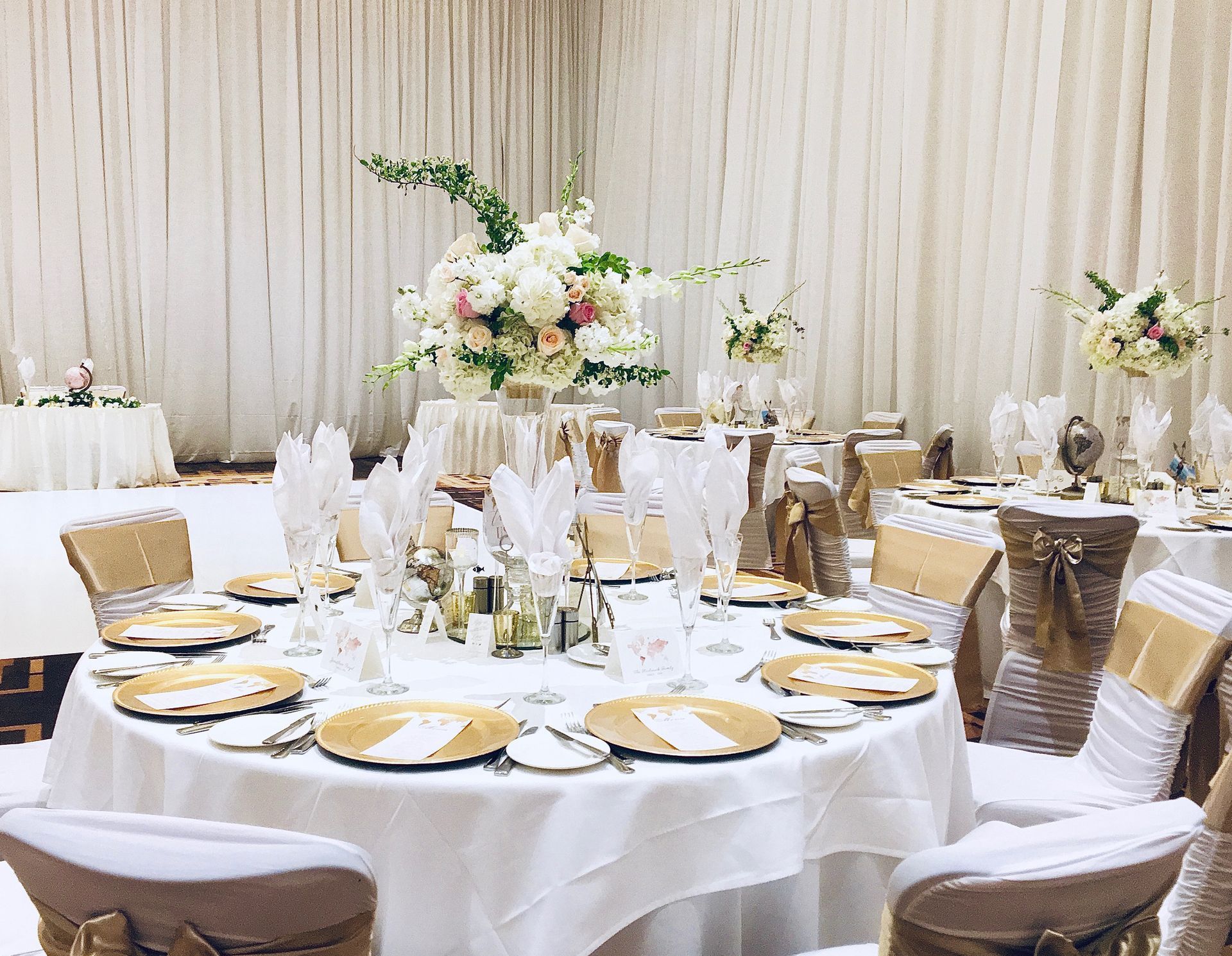 A room filled with tables and chairs set up for a wedding reception.