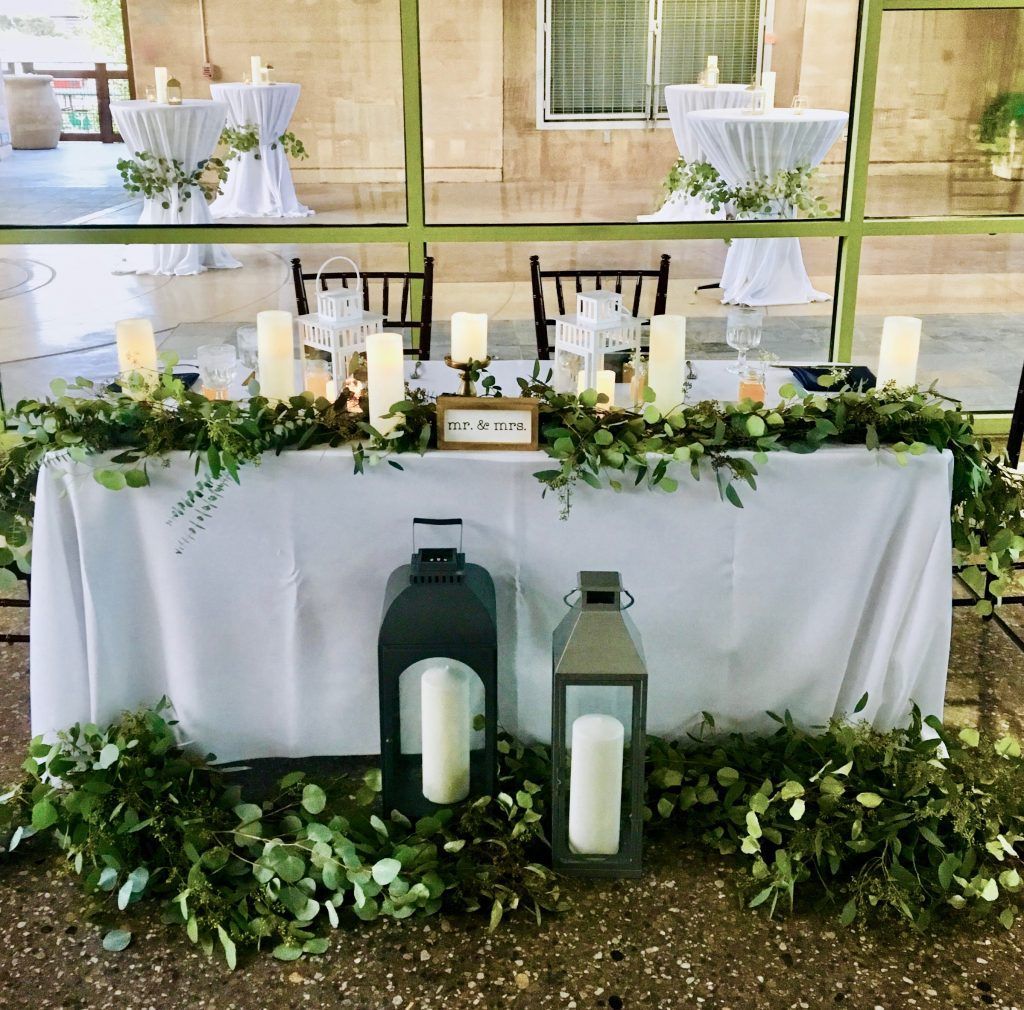 A table with candles and flowers on it in front of a window.