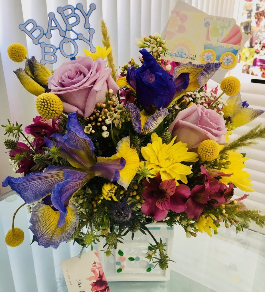 A bouquet of flowers on a table with a card that says baby boy