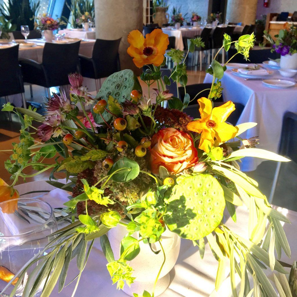 A vase of flowers sits on a table in a restaurant