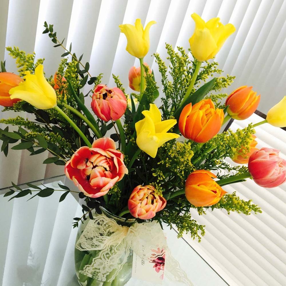 A vase filled with yellow and orange flowers sits on a table