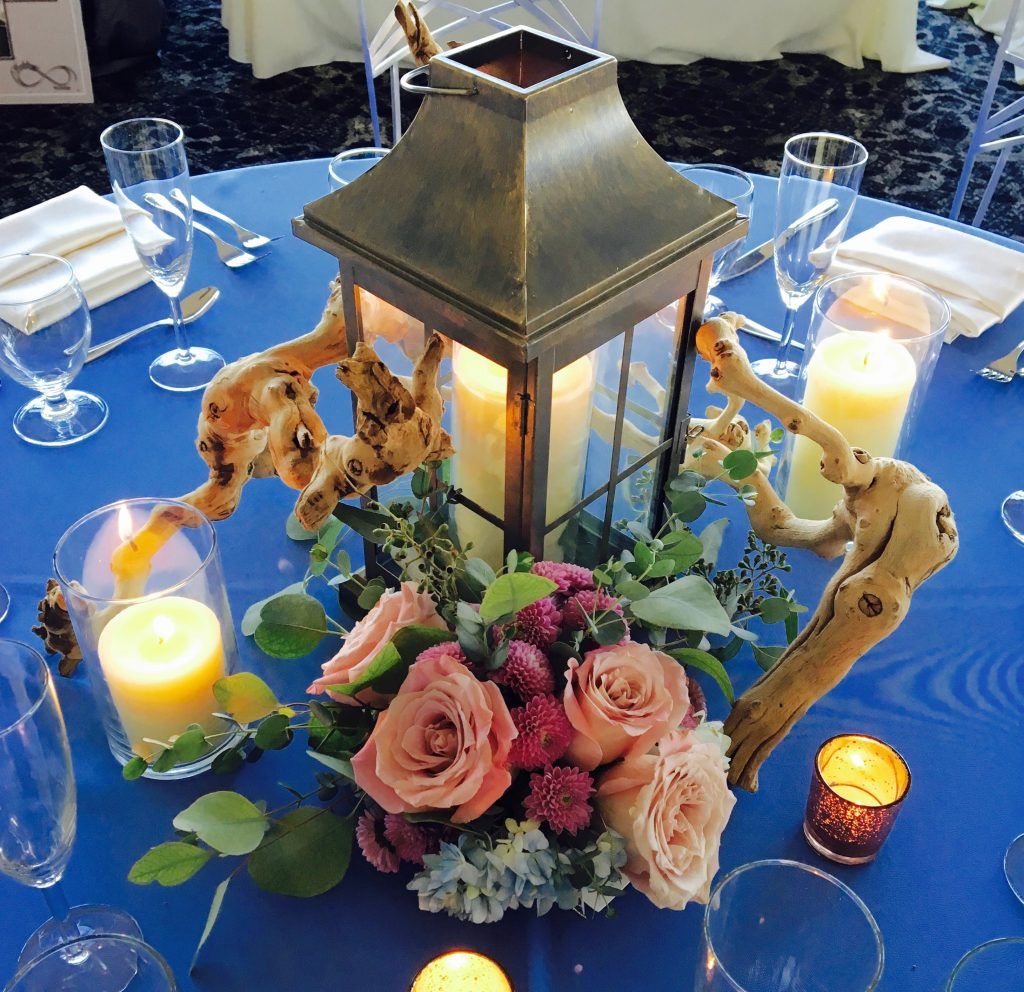 A table setting with a lantern filled with flowers and candles