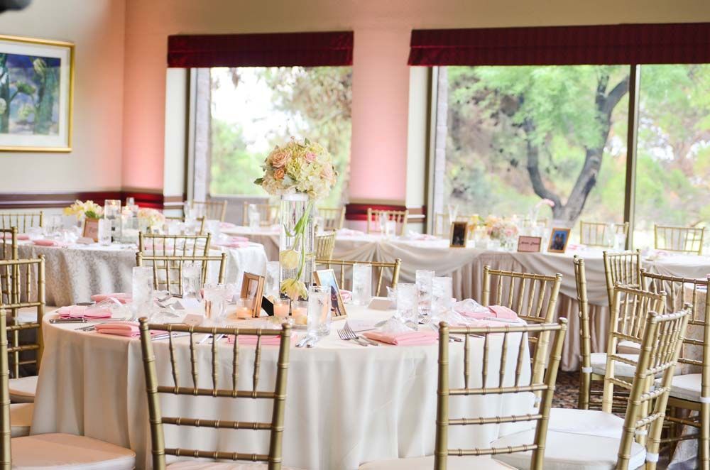 A room filled with tables and chairs set up for a wedding reception.