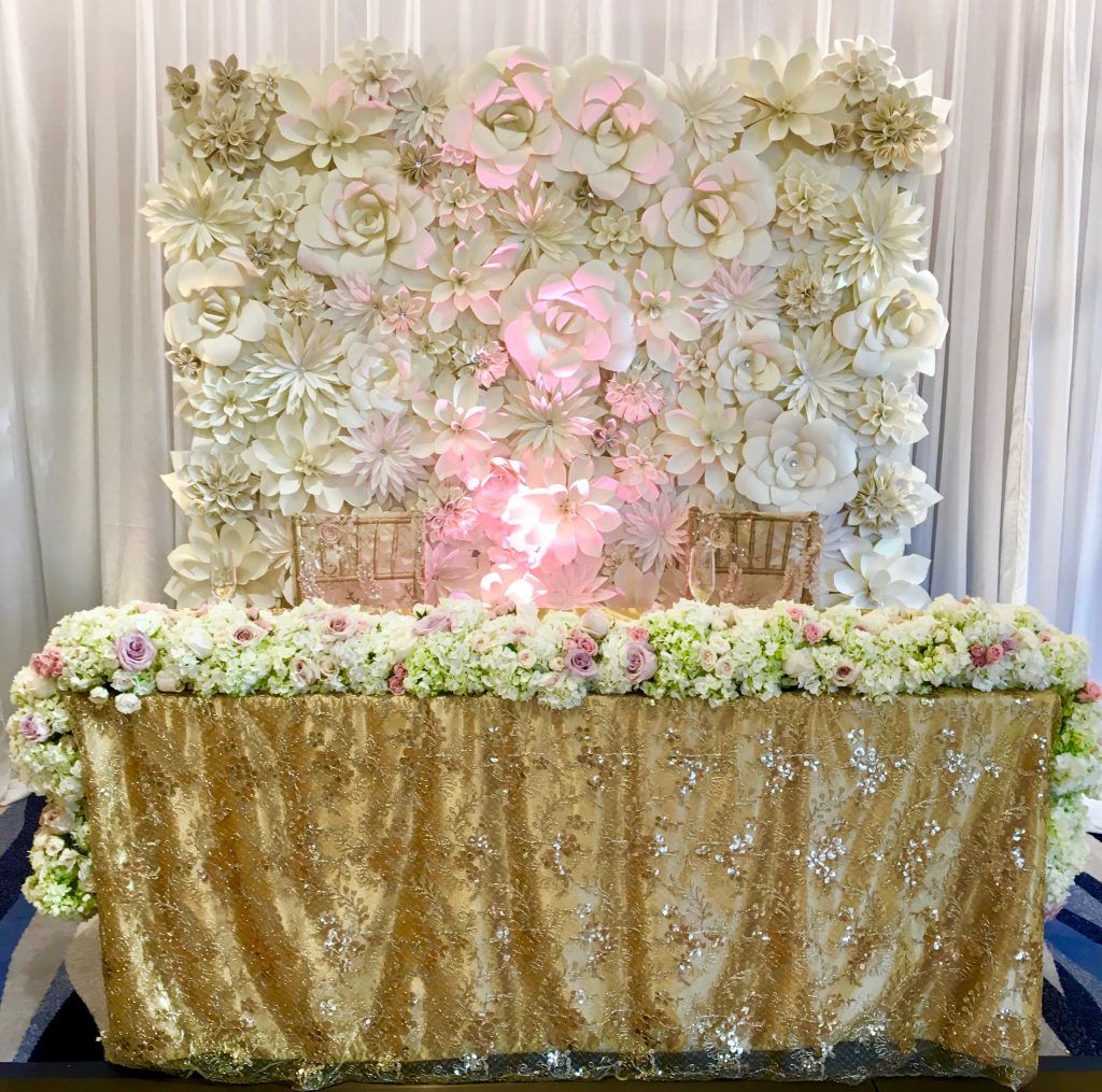 A table with a gold tablecloth and flowers on it.