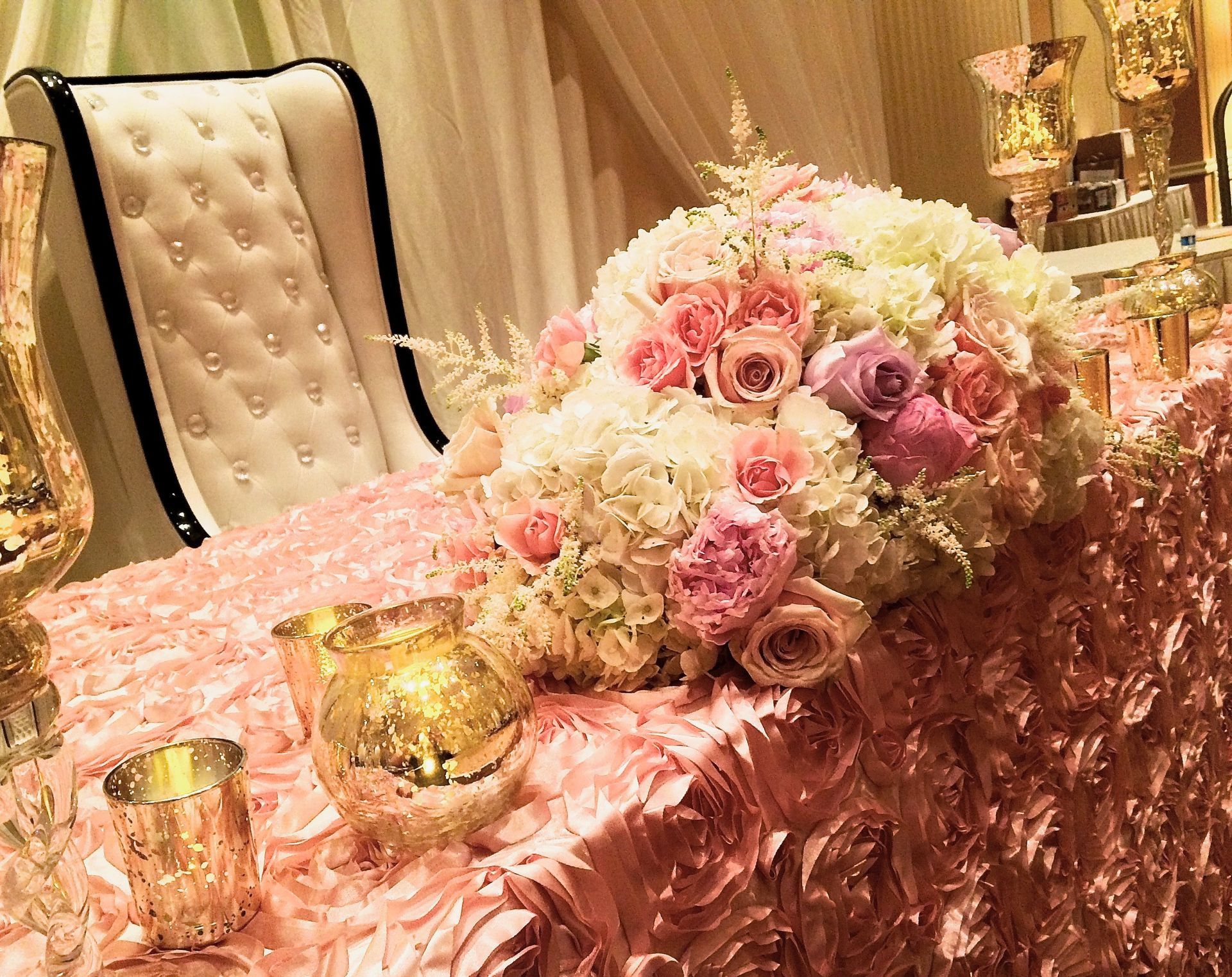 A table with flowers and candles on it and a chair.