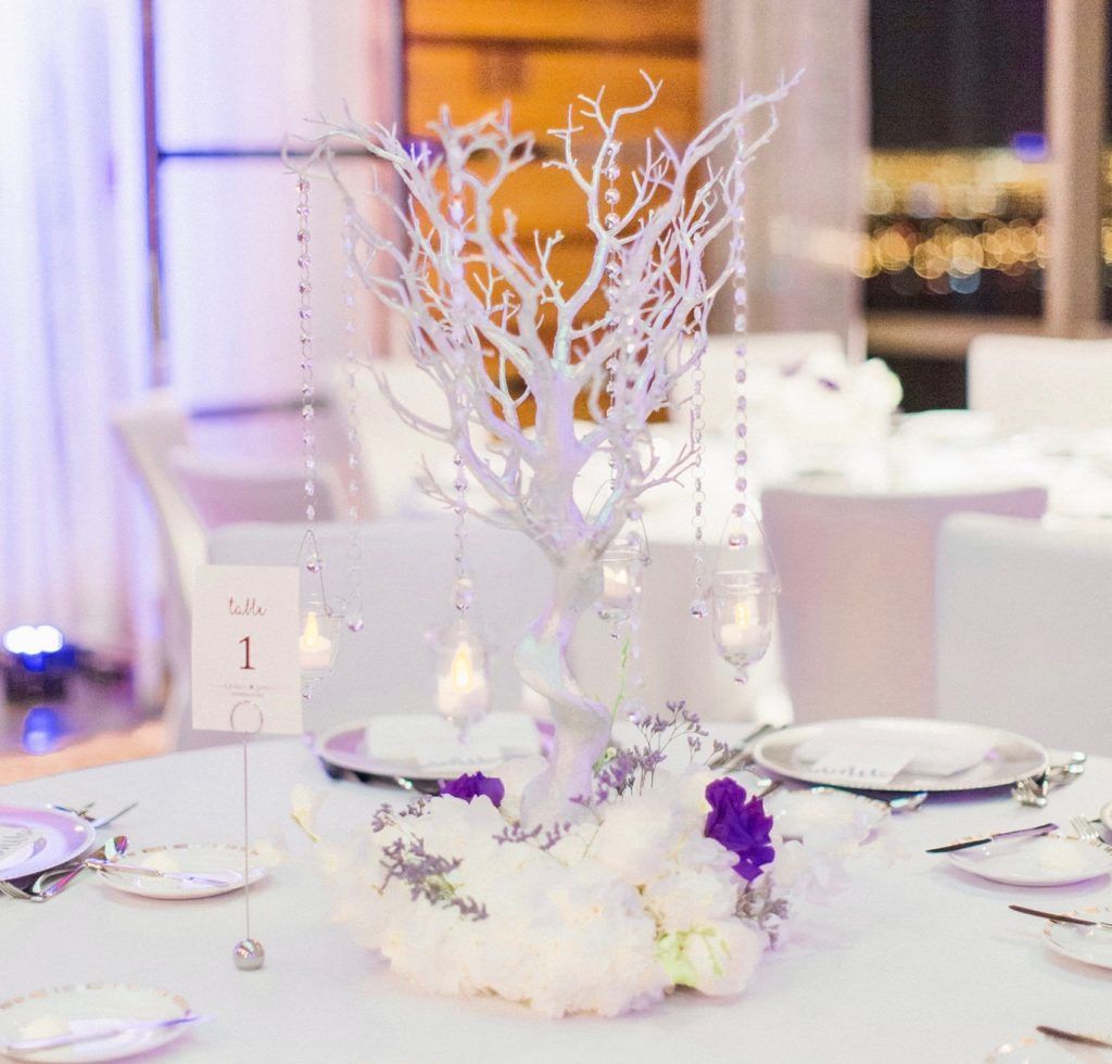 A table set for a wedding reception with a white tree centerpiece