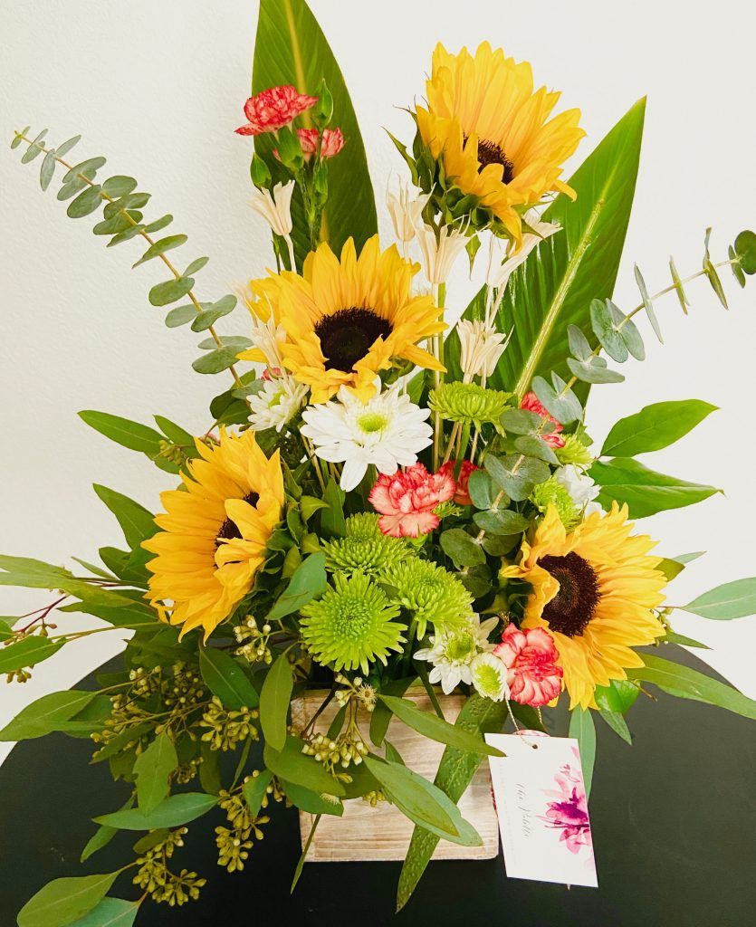 A bouquet of sunflowers and other flowers in a wooden box