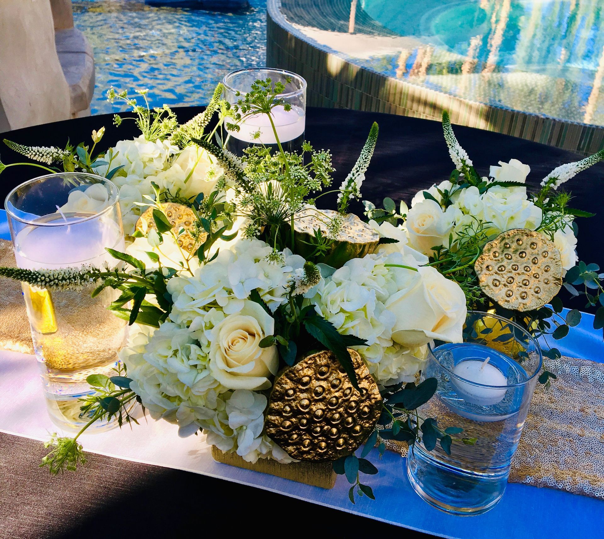 A table with flowers and candles on it in front of a pool.