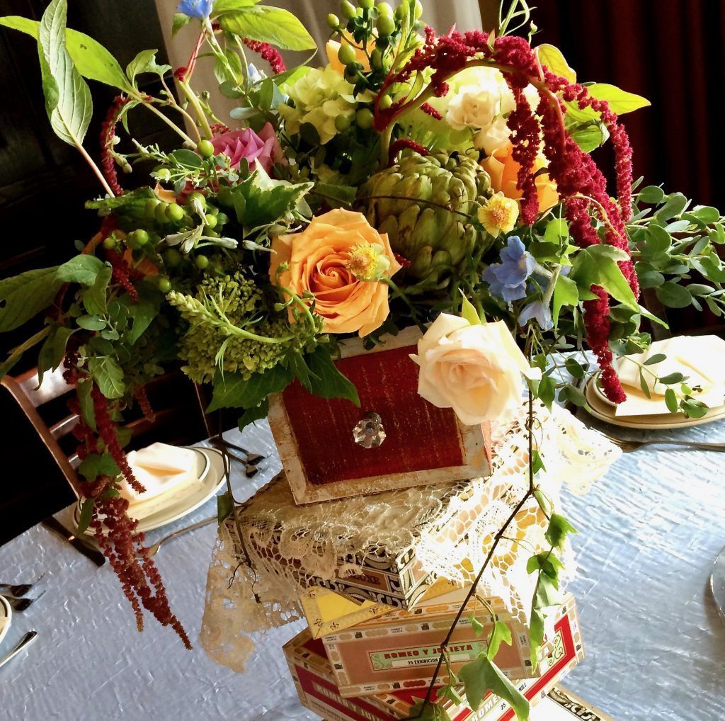 A vase of flowers sits on top of a stack of books
